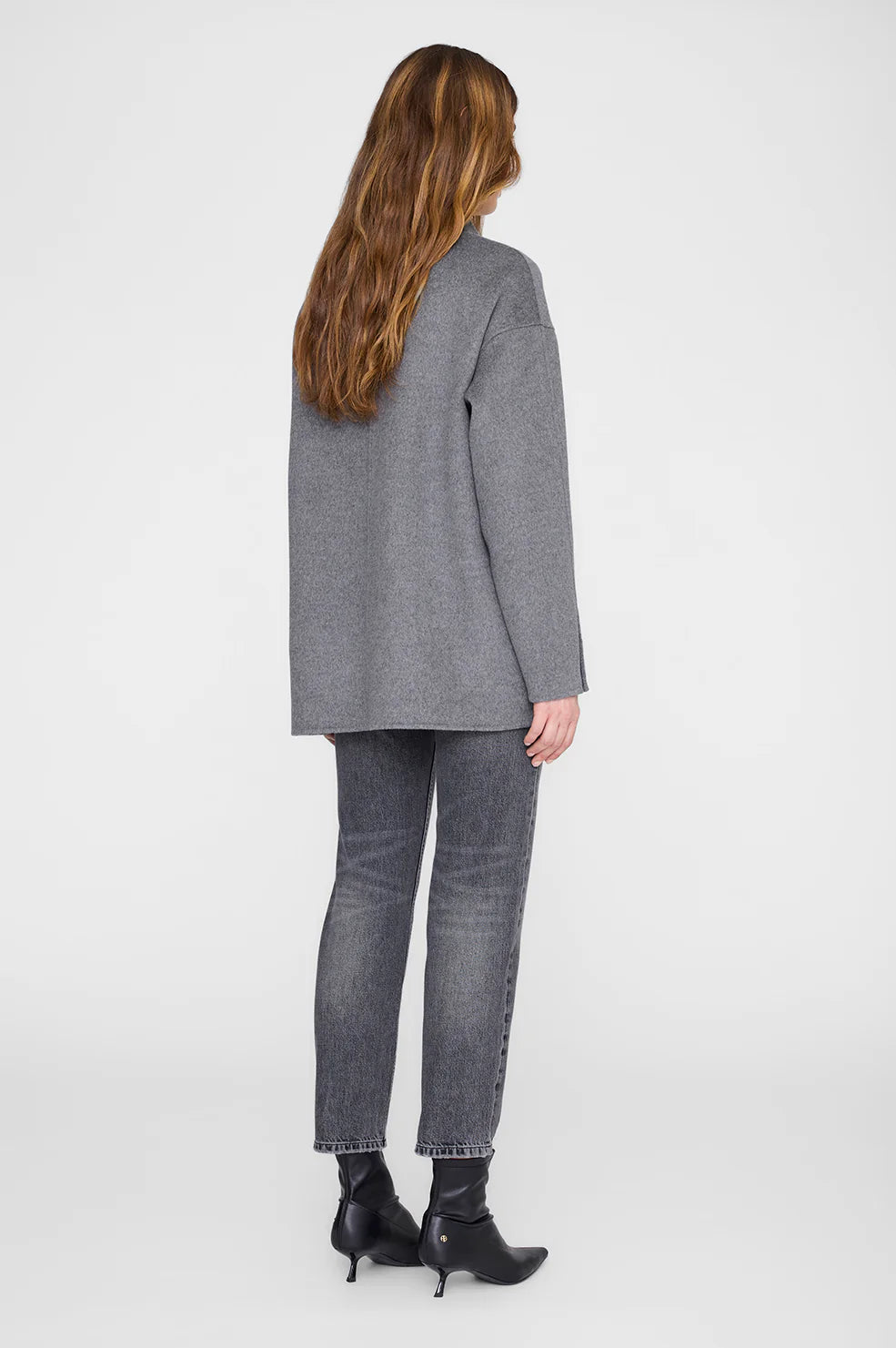 Person wearing a gray blazer and jeans on a white background