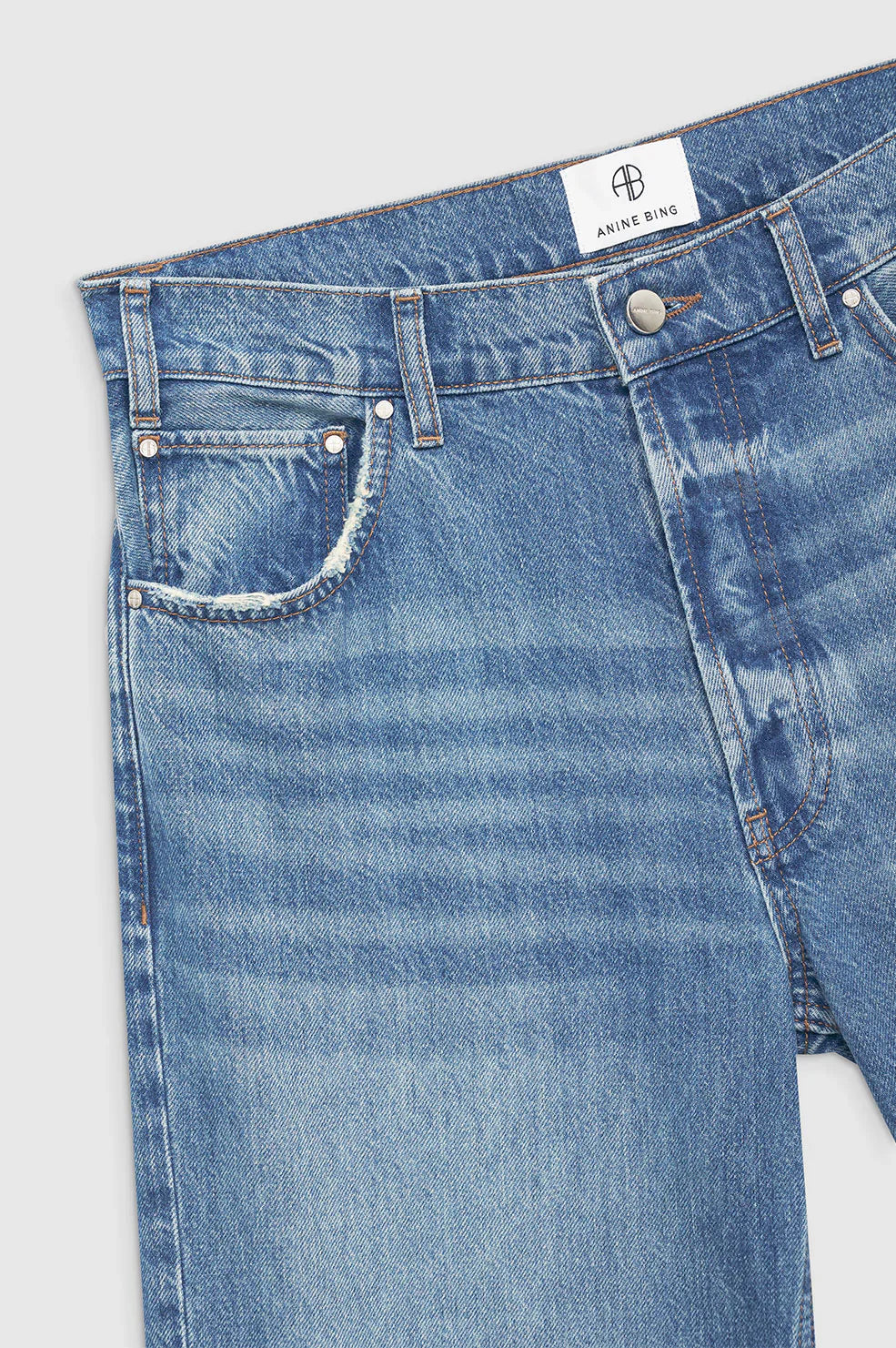 Close-up of blue jeans with a brand label on a light gray background