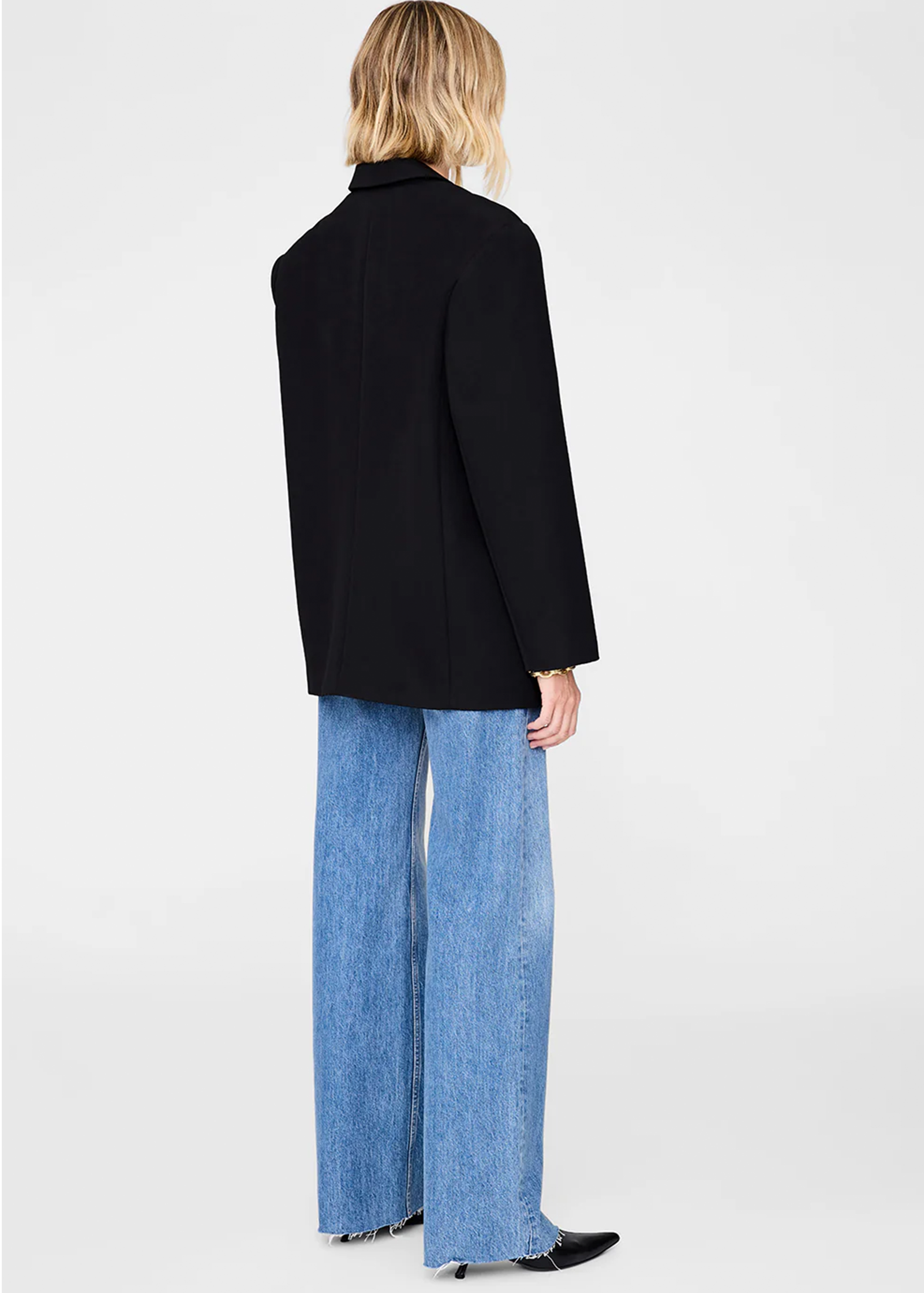 Person wearing quinn black blazer from anine bing and blue jeans on a white background