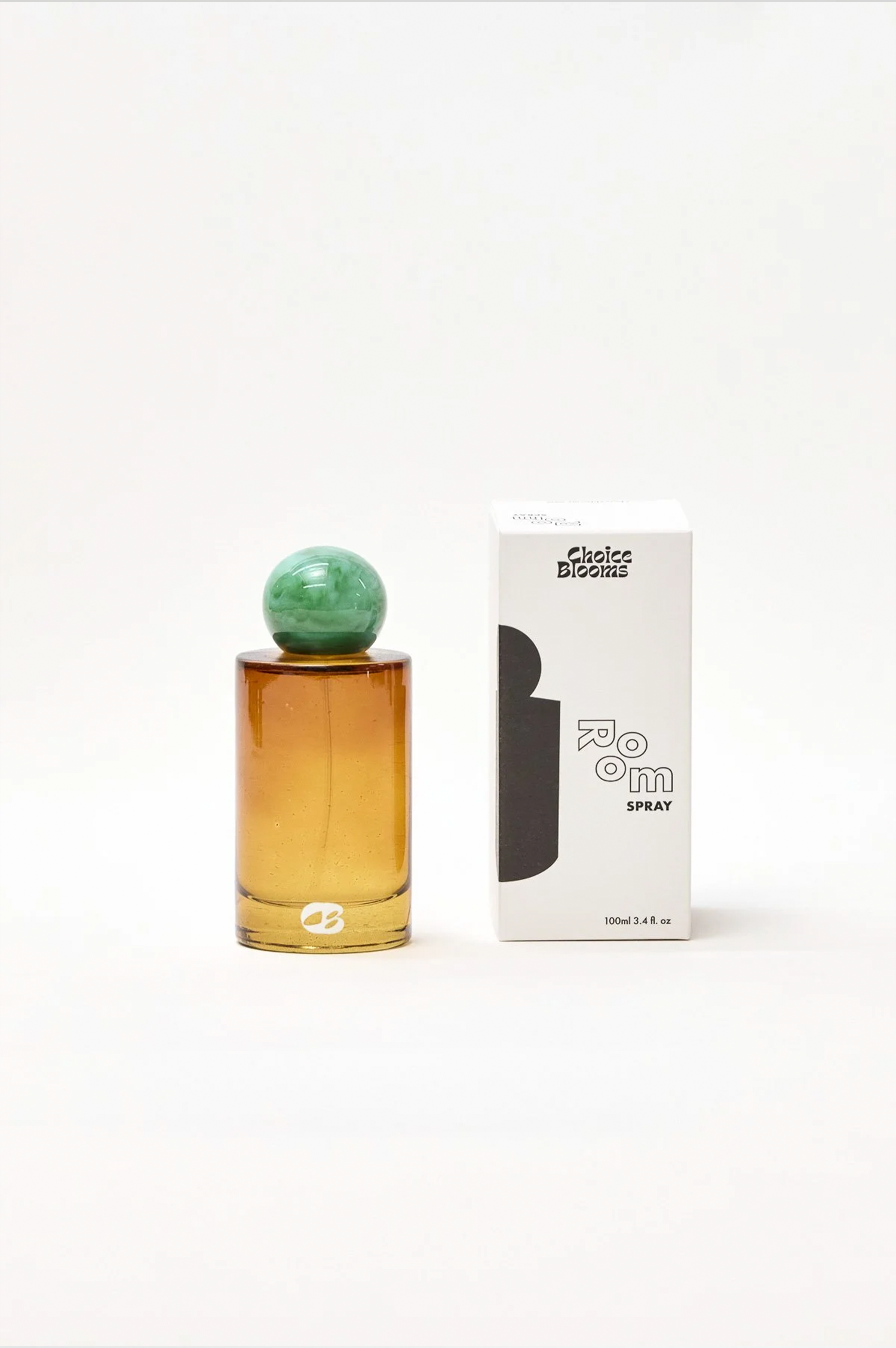 Perfume bottle with green cap and amber base next to its packaging on a white background