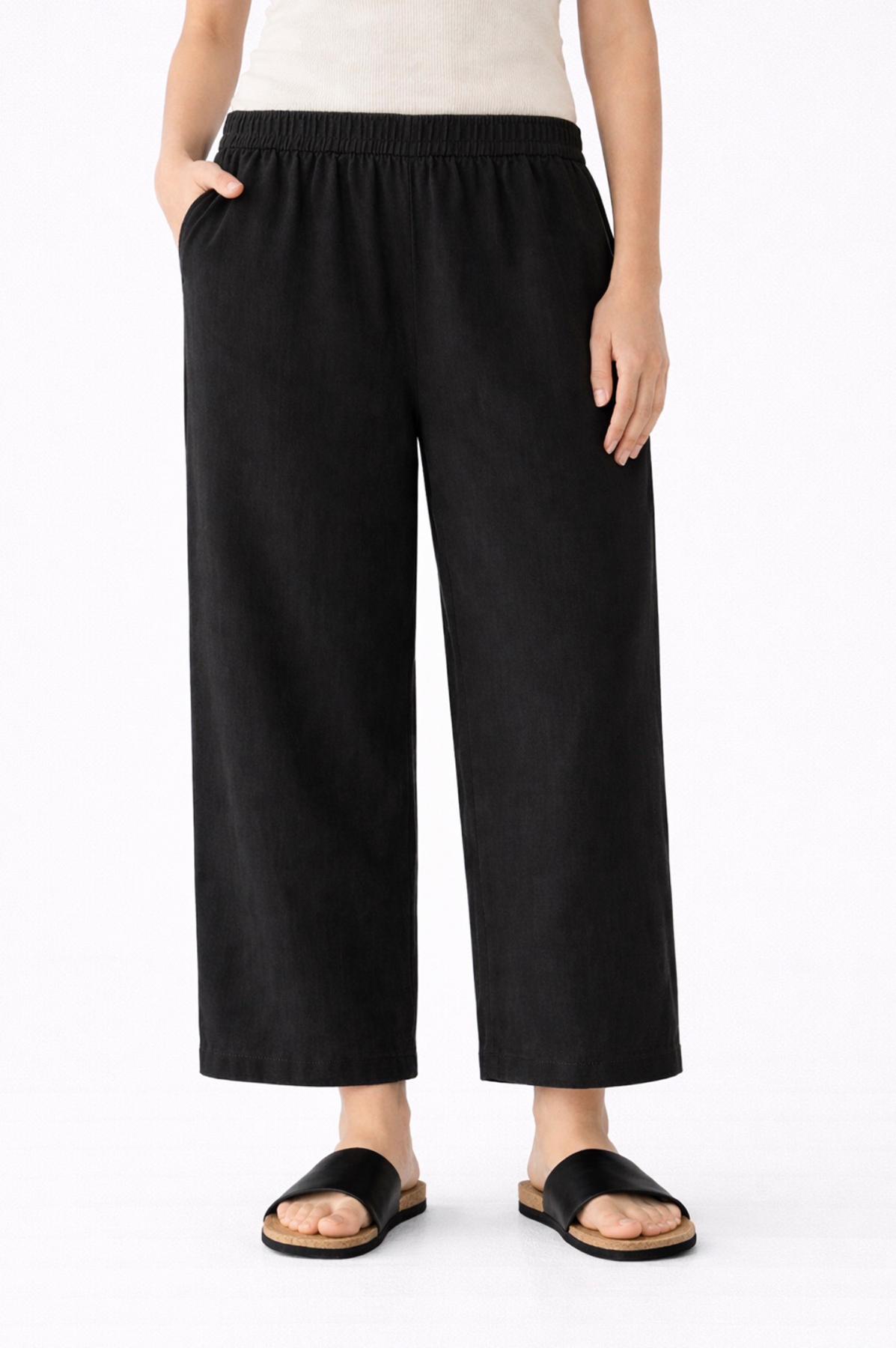 Person wearing black wide-leg linen pants on a white background