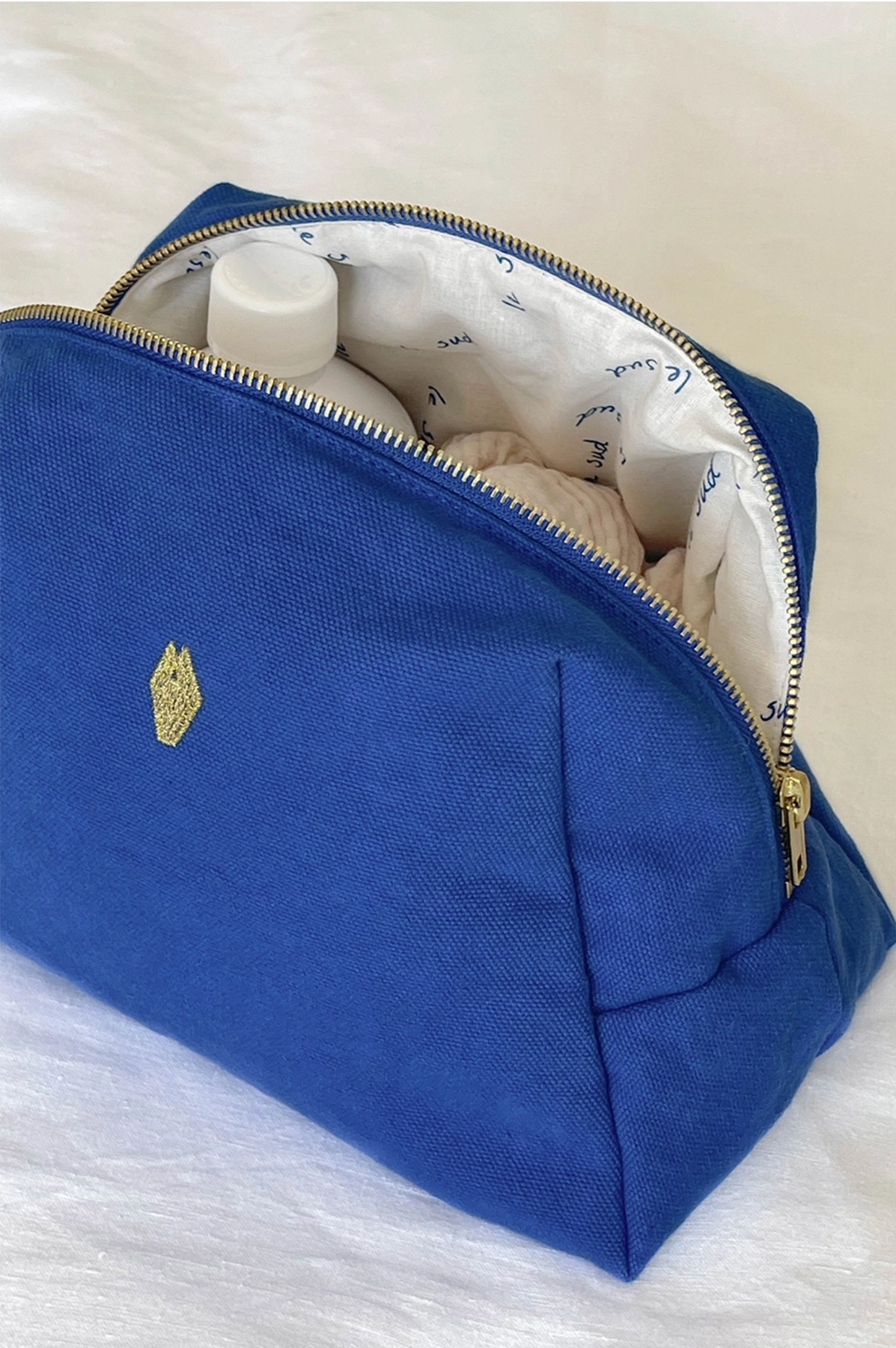 Blue toiletry bag with gold emblem on a white background