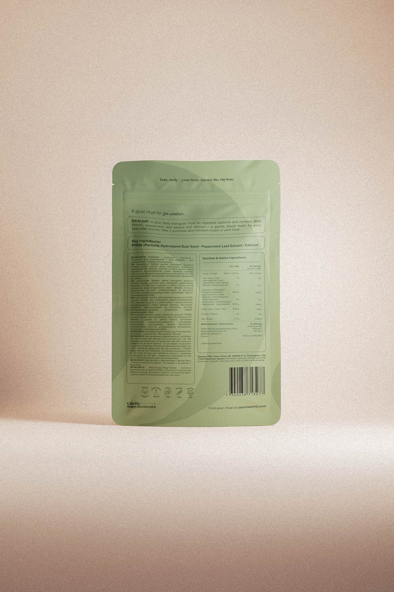 The back of a light sage green stand-up pouch packaging, featuring printed text, nutritional facts, and a barcode, set against a solid beige background.