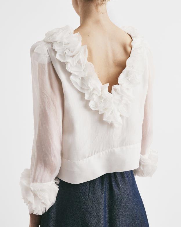 White blouse with ruffled sleeves and open back on a white background