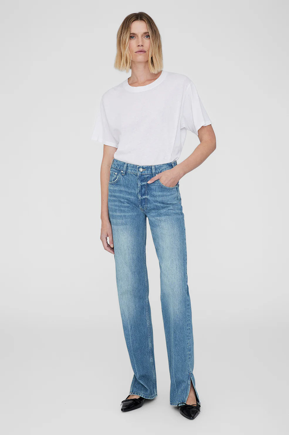 Woman wearing a white t-shirt and blue jeans on a white background