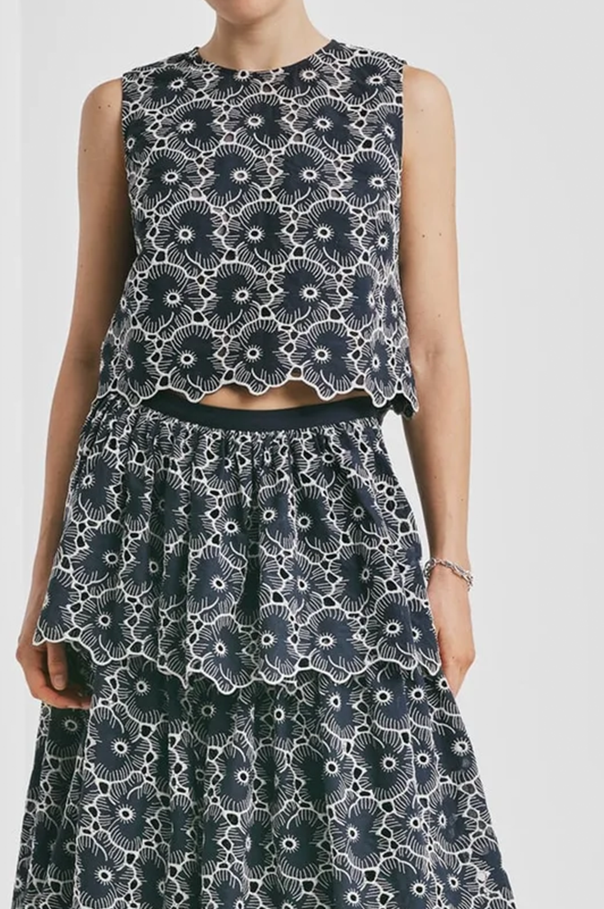 Person wearing a black and white floral sleeveless top and skirt set on a white background