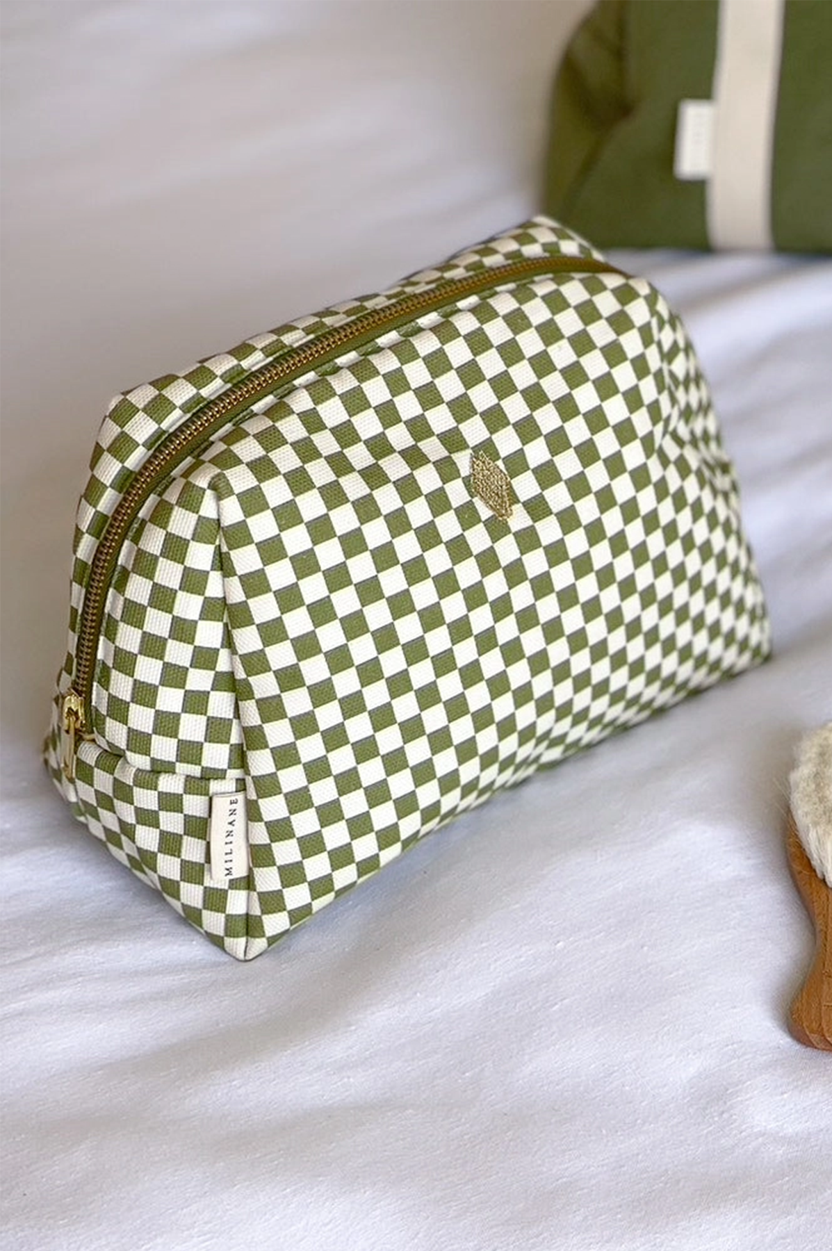 Green and white checkered pouch with a gold zipper on a white surface.