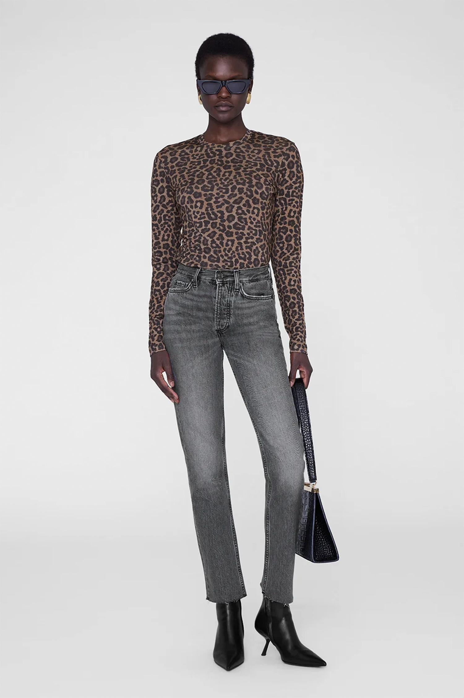 Person wearing a leopard print top and gray jeans on a white background