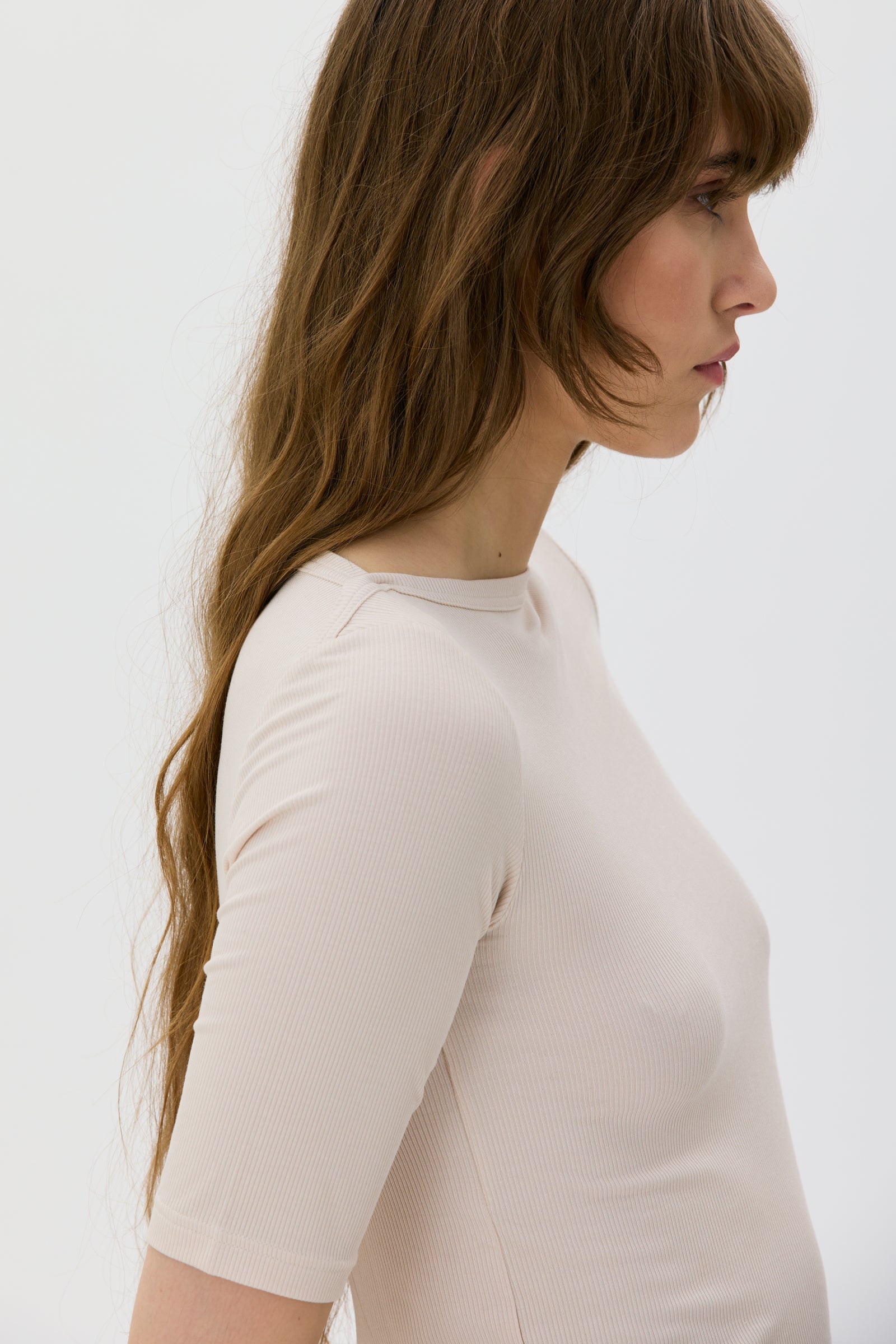 Woman wearing a beige top against a white background