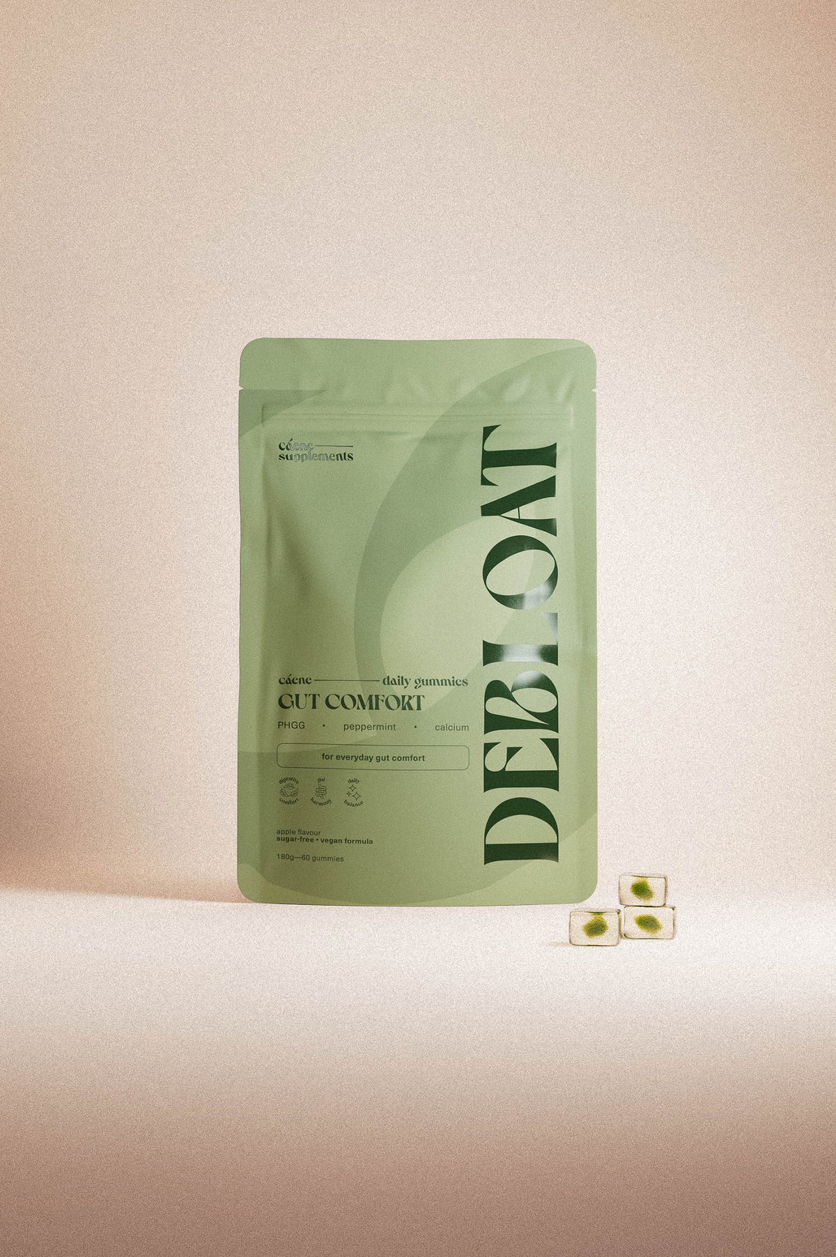 A light sage green stand-up pouch labeled 'DEBLOAT' and 'CUT COMBINE' with small green oval supplement capsules placed beside it on a warm beige background.