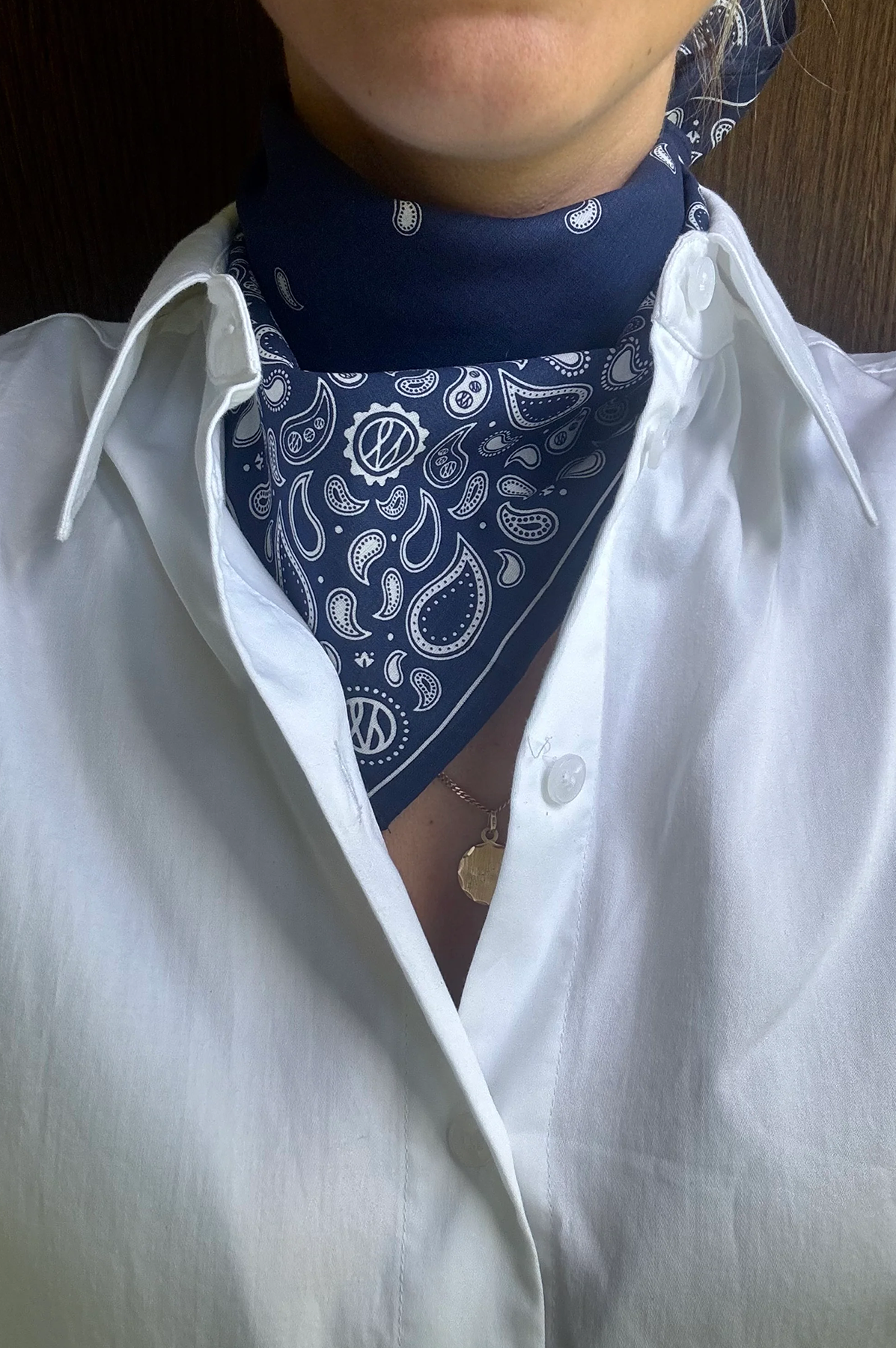 Person wearing a white shirt with a blue bandana around their neck.