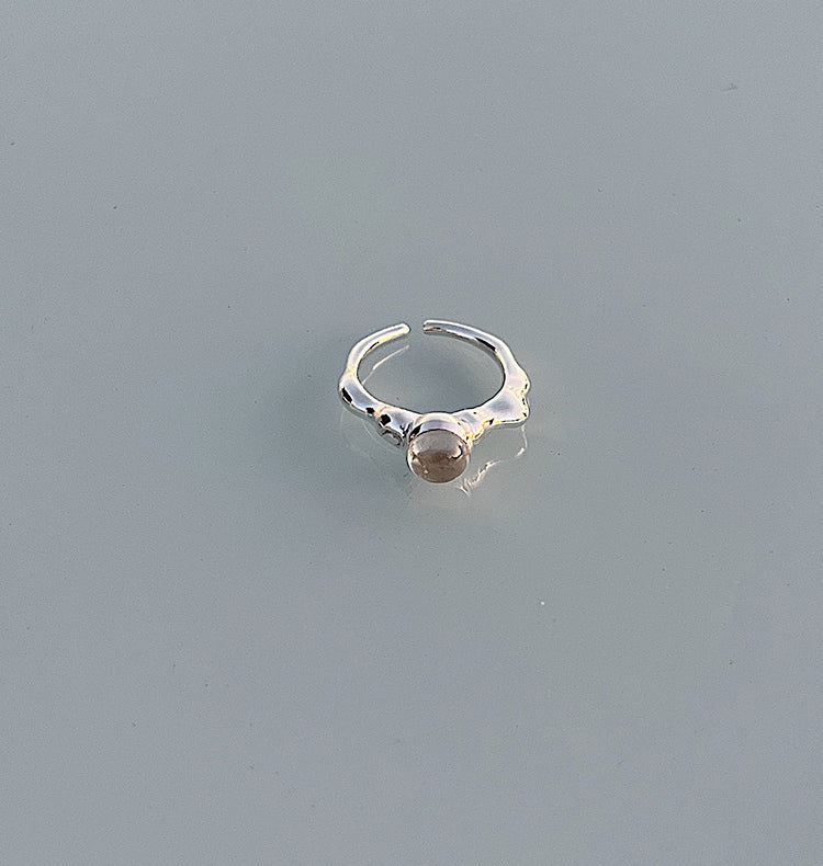 Silver ring with a small gemstone on a light gray background