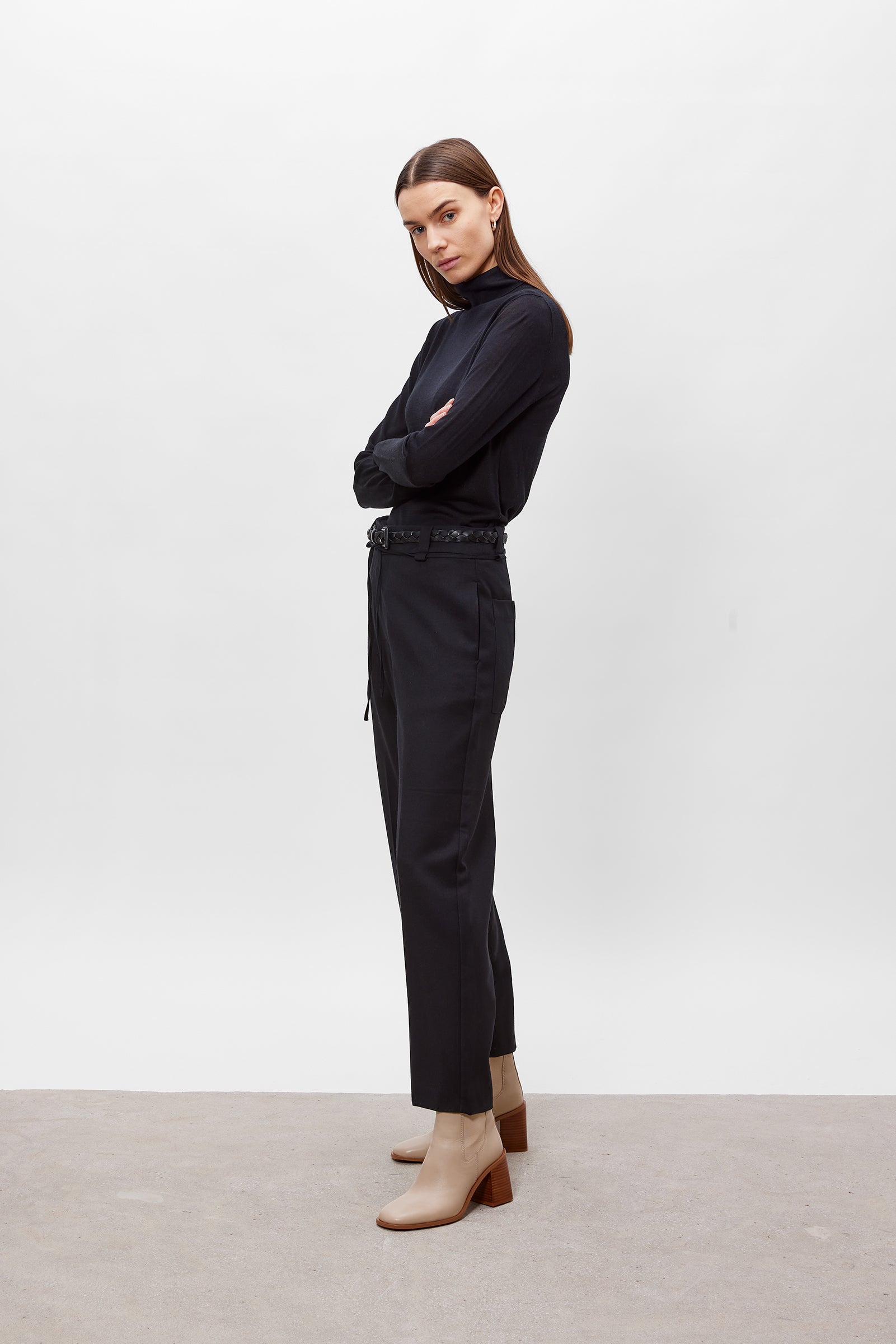 Woman wearing a black outfit with beige boots against a white background