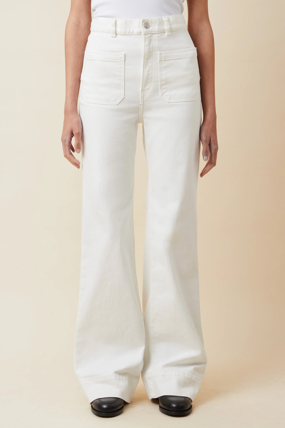 Person wearing st monica white wide-leg and low waist jeans from jeanerica on a beige background