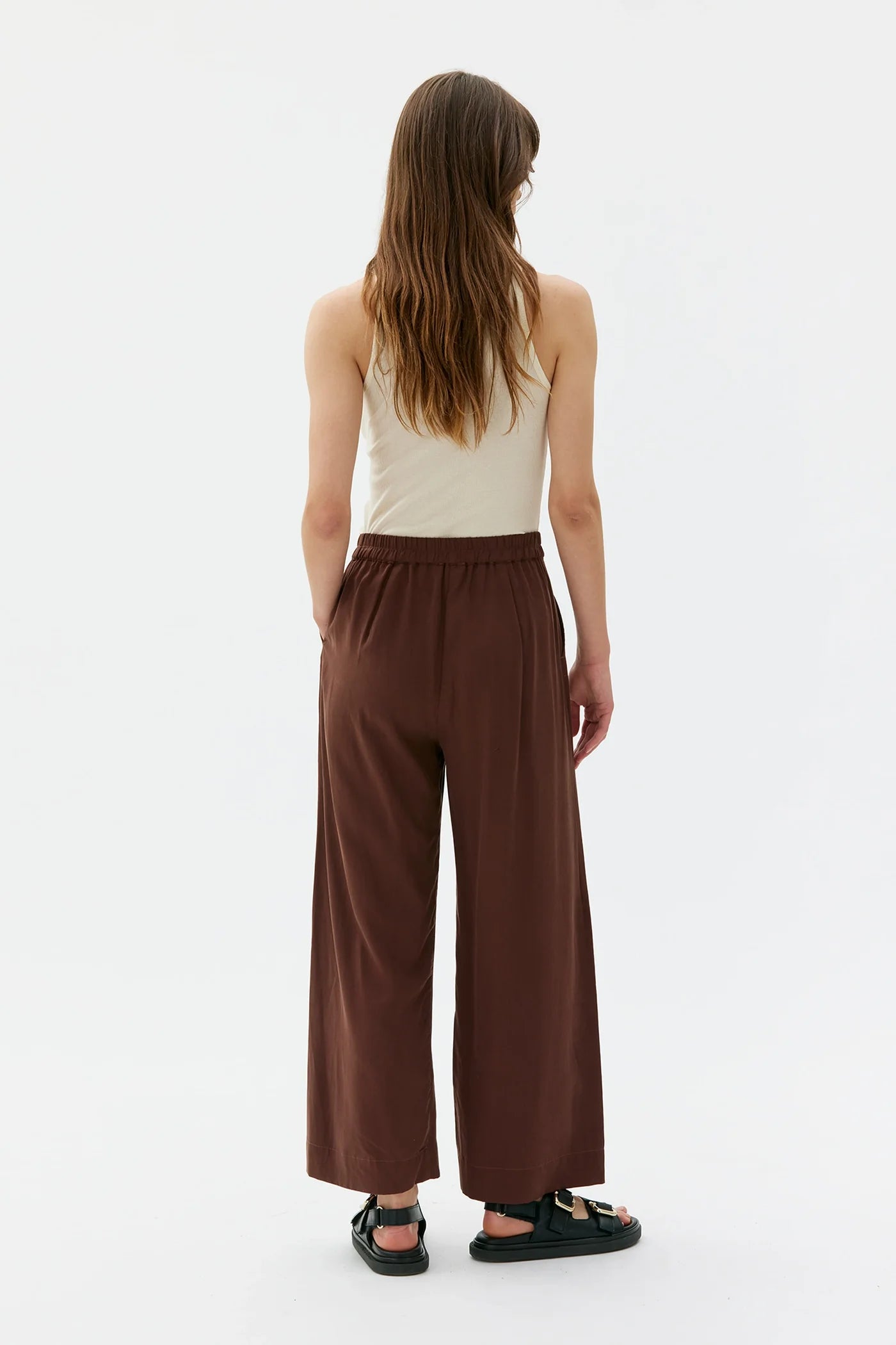 Woman wearing a beige top and brown wide-leg Thea pants from maska on a white background